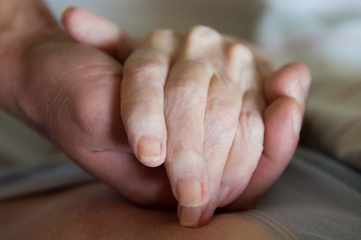 Ein Altenpfleger hält in einem Pflegeheim die Hand einer Frau (Symbolbild)